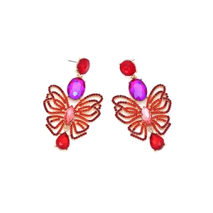 Detailed close-up of butterfly earrings with red crystals and purple oval gemstones