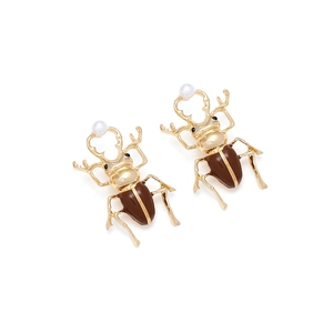 Detail of beetle earrings with brown enamel shells, gold finish, and white pearl heads