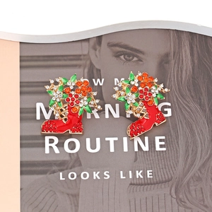 Boucles d'oreilles bottes de Noël avec strass rouges et fleurs sur fond de magazine