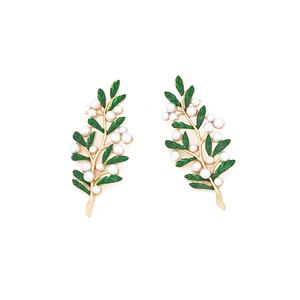 Detail of elegant gold branch earrings with green enamel leaves and faux pearls