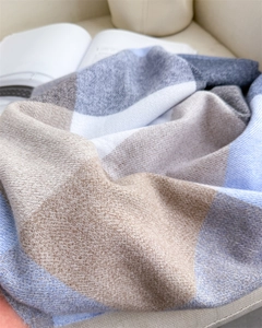 Texture détaillée d'une écharpe à carreaux bleue et beige avec des fibres douces style cachemire