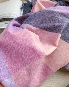 Gros plan sur une écharpe douce à carreaux rose et violet avec détails de franges fines