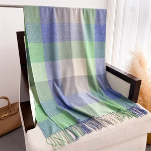 Détail d'une écharpe à carreaux bleu et vert avec de longues franges sur une chaise