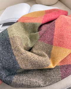 Gros plan sur la texture d'une écharpe à carreaux épaisse avec pompons colorés et maille