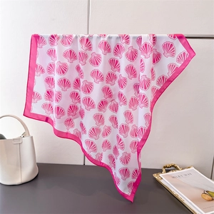 Silk-feel square scarf with pink shell prints and wide border hanging over a table