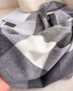 Vue macro d'une écharpe à carreaux gris et beige montrant le tissage sergé épais