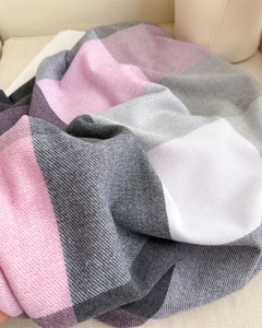 Gros plan d'une écharpe à carreaux rose et gris montrant la texture douce du tissage