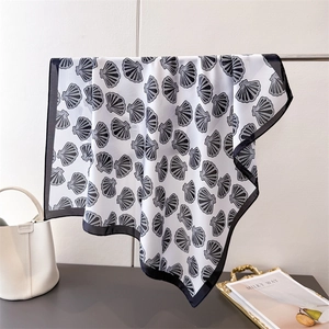Detail view of ocean-inspired silk scarf with black seashell print and sleek borders