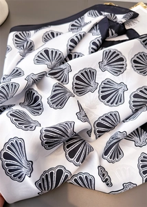 Detailed view of white seashell print on premium silk-like fabric with elegant black border