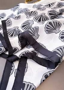 Detailed view of marine shell print on silky scarf with elegant black border trim