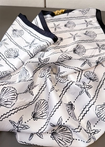 Detailed view of white faux silk scarf with black shell print and gold ring buckle