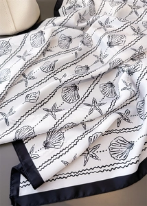 Close-up of silk scarf with black seashell prints and starfish on white background