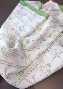 Detail of silk-like scarf featuring sea salt shell patterns and green rolled edges