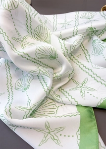 Macro detail of silk scarf showing seashell prints and smooth draped fabric texture