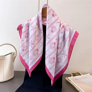 Elegant silk scarf with shell prints draped over black shirt with luxury props