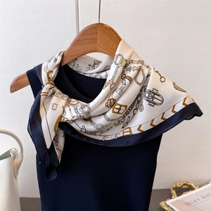 Détail d'un foulard en soie à imprimé équestre sur un haut en tricot noir élégant