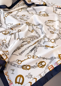 Détails macro du foulard en soie montrant des motifs équestres et des chaînes dorées