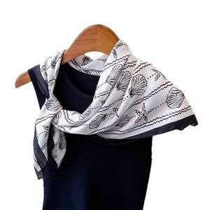 Elegant sea shell print silk scarf with black and white ocean patterns on a wood hanger