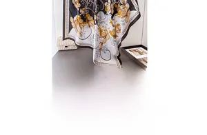 Detailed view of floral satin silk scarf in black and gold on a styled desk surface