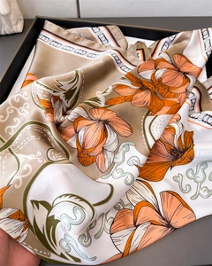 Detail of satin square scarf with orange floral prints and elegant chain patterns