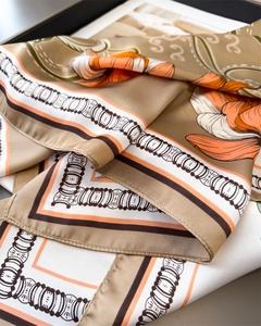 Detail of satin silk scarf featuring luxury floral patterns and elegant khaki and orange hues