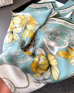 Close-up of elegant satin scarf featuring light blue silk with yellow lily floral prints