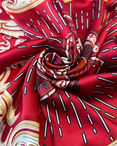 Close-up of red silk satin scarf featuring intricate vintage patterns and a glossy texture