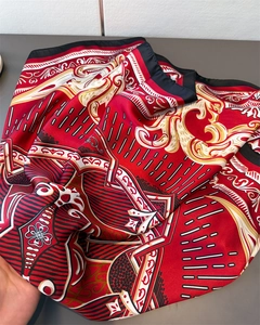 Detail of red satin scarf with golden baroque patterns and smooth glossy finish