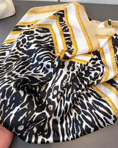 Detail of silk scarf with leopard print and gold chain borders on a white base
