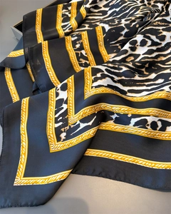 Close-up of satin silk scarf featuring leopard print and golden chain patterns