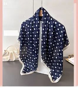 Detail of silk-like scarf with white polka dots hanging on a wooden hanger with pearls