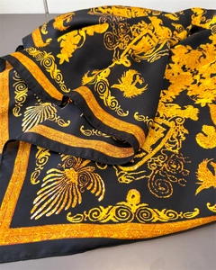 Détail macro d'un foulard en satin baroque avec motifs floraux dorés sur tissu noir
