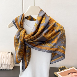 Foulard en satin gris avec motifs baroques dorés présenté sur un mannequin blanc