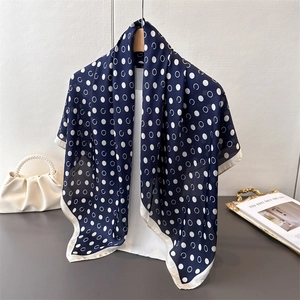Close-up of geometric polka dot silk scarf with navy blue and white pattern on a wooden hanger