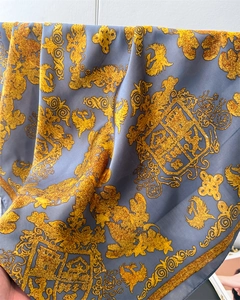 Détail d'un foulard baroque vintage en tissu satiné bleu avec des motifs héraldiques dorés