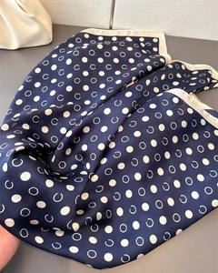 Detail of navy blue satin scarf with geometric polka dot pattern and cream hem