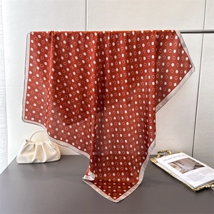 Polka dot silk-like square scarf in vibrant orange with elegant pearl bag and decor
