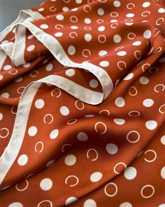 Macro shot of silk satin scarf showing smooth texture with white polka dots pattern
