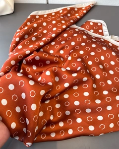 Detailed close-up of geometric polka dot silk-like scarf texture and rolled edge