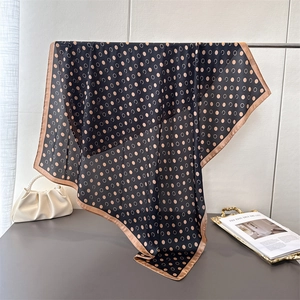Elegant polka dot satin silk scarf with beige borders hanging on a display stand