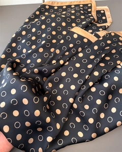 Macro shot of geometric gold polka dots and C-pattern on black silk scarf texture