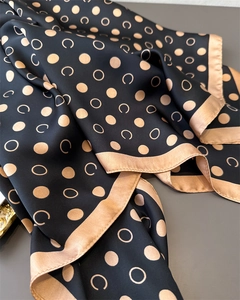 Close-up of silk-like geometric polka dot scarf with luxury black and gold satin textures