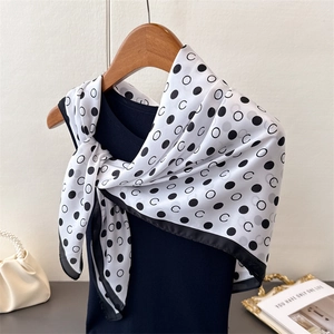 Detail of geometric polka dot silk scarf with letter C pattern tied on a wooden hanger