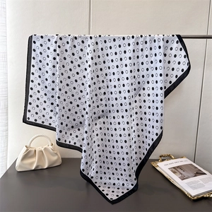 Elegant black and white polka dot silk square scarf hanging with fluid drape texture