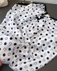 Macro view of geometric polka dot silk scarf with black and white patterns and hemmed edges