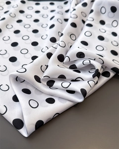 Detail of white silk scarf showing black polka dots and minimalist geometric prints