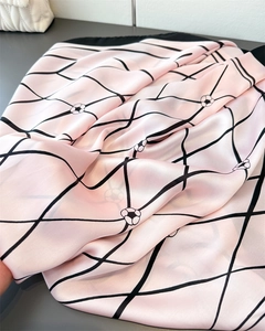 Close-up of pink satin scarf with black grid pattern and white camellia floral details