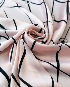 Detail of pink satin scarf featuring black grid and camellia floral patterns in rose fold