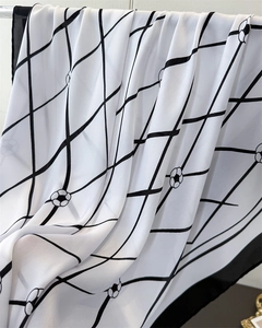 Detail of floral printed satin silk scarf showing translucent chiffon texture and grid pattern