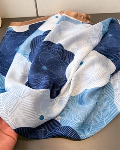 Detail of silk-like satin floral scarf featuring elegant blue and white wavy patterns